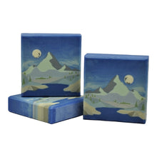 Lade das Bild in den Galerie-Viewer, Drei rechteckige Stücke handgemachter Seife mit einem Landschaftsmotiv, das Berge, einen Fluss, Steine und einen Mond zeigt.