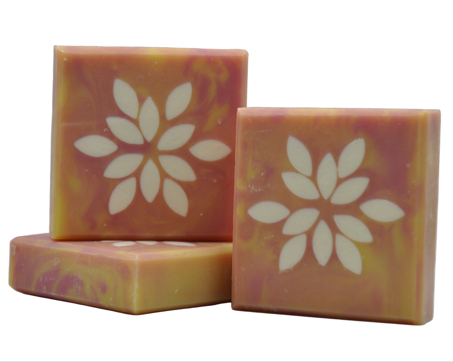 Star Soap – drei handgemachte Seifenstücke in warmen, wirbelnden Rosa- und Goldgelbtönen mit einem cremefarbenen Sternblumenmuster, das sich durch das Seifenstück zieht, präsentiert auf weißem Hintergrund.