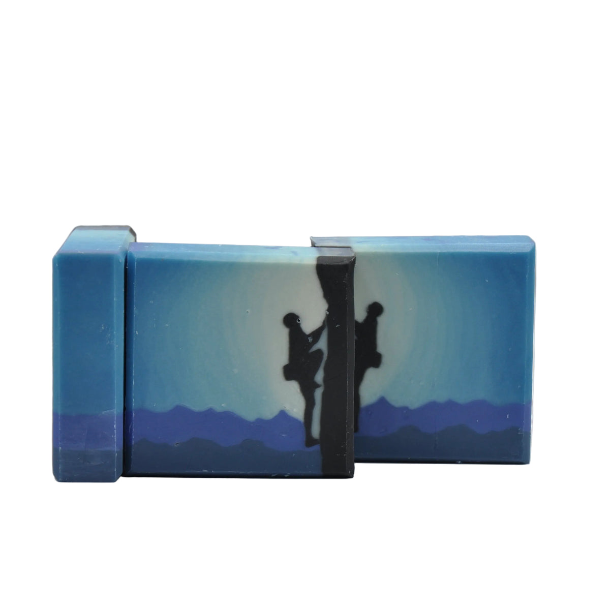 Nahaufnahme zweier veganer Seifen mit blauem Farbverlauf, schwarzer Kletterer-Silhouette und Bergsilhouette, Duft Nautic
