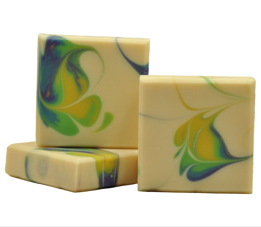 Three swirled soap bars with green, blue, and yellow colors on a white background