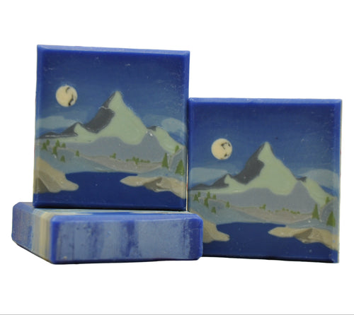 Three blue soap bars with mountain and moon designs on a whitw background